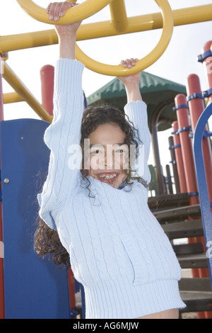 Dix ans smiling hispanic girl hanging on monkey bars aire de l'âge scolaire en santé éducation vie active force Banque D'Images