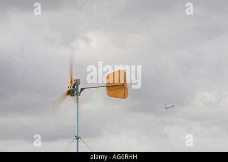 Le réchauffement le ciel et l'enfer un avion décolle passé une éolienne utilisée pour alimenter le camp climatique Banque D'Images