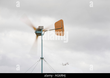 Le réchauffement le ciel et l'enfer un avion décolle passé une éolienne utilisée pour alimenter le camp climatique Banque D'Images