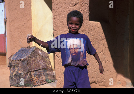 Agadez Niger Boy holding lizard's cage et vêtus de T-shirt avec l'image d'Oussama Ben Laden Banque D'Images