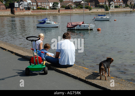 Groupe familial et chien sur le mur du port des yachts amarrés à Emsworth avec Banque D'Images