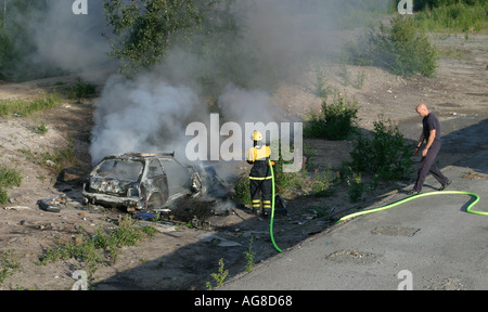 Voiture brûlée et un pompier pour éteindre le feu , Finlande Banque D'Images