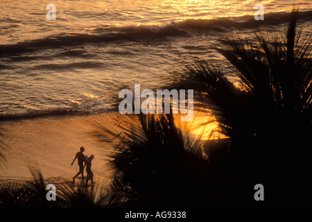 Voir les palmiers du couple en train de marcher le long de plage au coucher du soleil Zihuatanejo Mexique parution du modèle de droit Banque D'Images