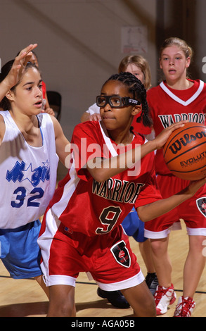Joueur de basket-ball féminin de la jeunesse se prépare à passer le ballon en le protégeant de l'attaque Banque D'Images