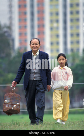 La Chine, Hong Kong, le grand père et sa petite-fille marcher avec oiseau en cage Banque D'Images