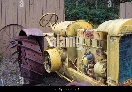 Vieux tracteur agricole jaune rouillé garé dans un cadre rural, mettant en valeur des décennies d'histoire agricole, États-Unis. Banque D'Images
