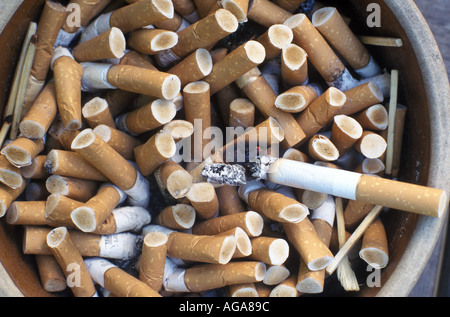 Un des brûlures de cigarette sur un cendrier plein de mégots. Banque D'Images