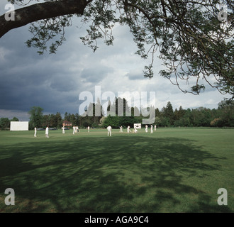 Une partie de cricket qui a eu lieu sur la place du village à Longparish Hampshire sur une journée d'été Anglais typique, avec du soleil et nuages Banque D'Images