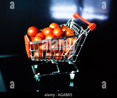 Mini caddie plein de mini tomates sur un fond noir Banque D'Images