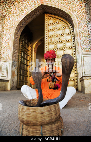 Charmeur de serpent en face du palais de ville complexe dans Jaipur spectacle deux cobras dans striking pose modèle indien libéré Banque D'Images