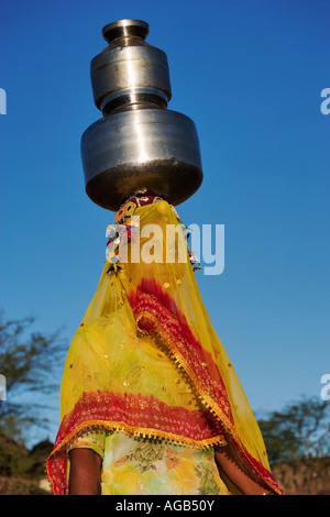 Femme portant de l'eau dans la façon traditionnelle d'un puits à l'extérieur de l'Inde Pushkar parution Modèle Banque D'Images