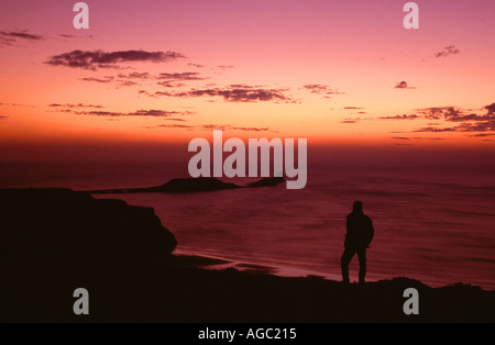Une figure qui se découpent SUR LE BAS RHOSSILI regardant le coucher de soleil sur la tête de vis sans fin, la péninsule de Gower, West Glamorgan, Pays de Galles, Royaume-Uni Banque D'Images