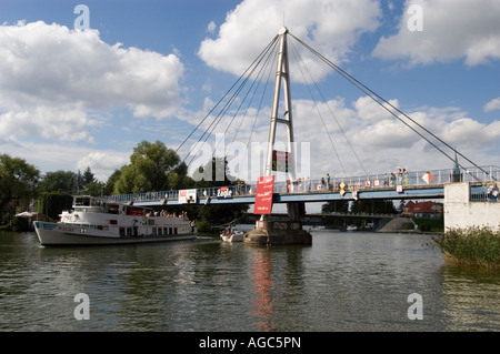 Pont piétonnier à Mikolajki, Mazurie, Pologne. Pont à haubans blanc au-dessus d'un lac avec un bateau de tourisme passant sous. Destination de voyage d'été. Banque D'Images