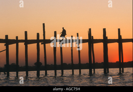 Au coucher du soleil, un moine TRAVERSE U BEIN BRIDGE,AMARAPURA PRÈS DE MANDALAY, Birmanie, Myanmar. C'est le plus long pont en teck DANS LE MONDE Banque D'Images