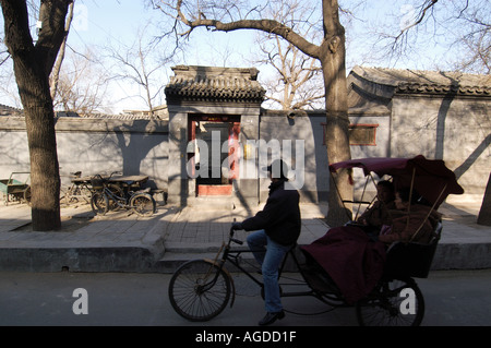 Les touristes sur un hutong tour passer l'entrée classique à une cour maison dans un hutong de Beijing en Chine Banque D'Images