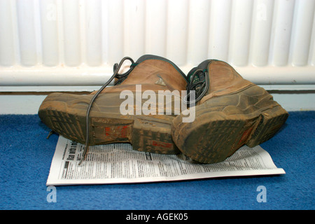 Bottes de randonnée le séchage sur sol, à côté du radiateur de chauffage central Banque D'Images