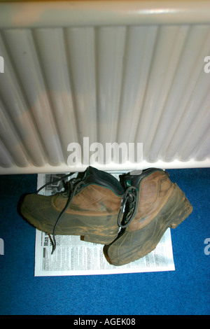 Bottes de randonnée le séchage sur sol, à côté du radiateur de chauffage central Banque D'Images