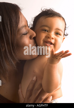 La mère et l'enfant en studio sur fond blanc. C'est mère de l'enfant s'embrasser sur la joue et l'enfant souffle un baiser. Banque D'Images