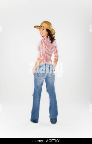 Young Caucasian woman wearing cowboy hat looking over Shoulder at viewer and smiling Banque D'Images