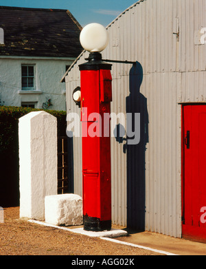 Ancienne station-service de style vintage en Irlande rurale avec un pompe à essence rouge à côté du garage gris Banque D'Images