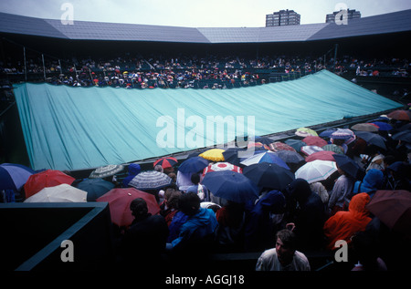La pluie arrête de jouer Wimbledon tennis Londres SW19 1980s Royaume-Uni. Terrains centraux couverts. Les fans s'assoient sous la pluie en attendant la reprise du match 1985 Angleterre Banque D'Images