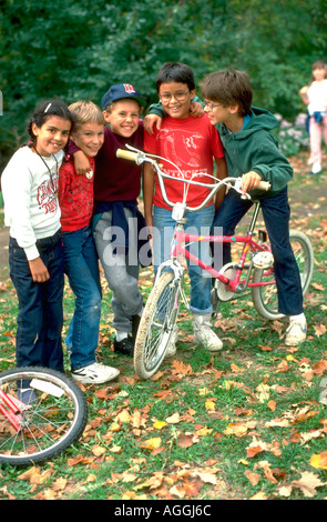 Cinq enfants âgés de 11 multiraciale souriante avec les bras sur les épaules en vélo. St Paul Minnesota USA Banque D'Images