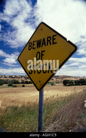 Méfiez-vous de l'Australie de stock attention panneau routier. Caractères noirs avec lettrage graphique jaune signe métallique et de la terre - le fond de ciel. Banque D'Images