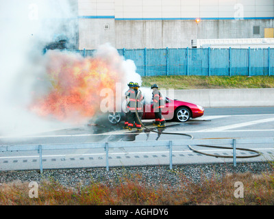 Les pompiers éteindre les feux d'une voiture sur l'autoroute Banque D'Images