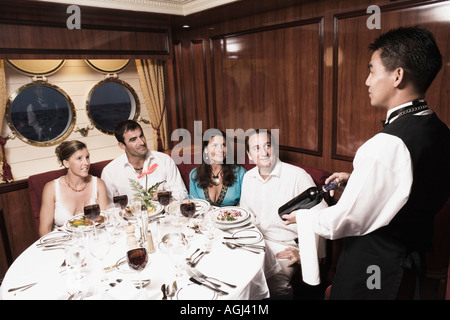 Waiter serving bouteille de vin pour deux couples adultes Banque D'Images