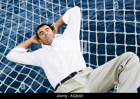 Mid adult man sleeping dans les filets d'un navire Banque D'Images