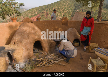 Les fours à pain de boue traditionnel berbère avaient tendance par des femmes en habits traditionnels locaux Atlas Maroc près de Marrakech Banque D'Images