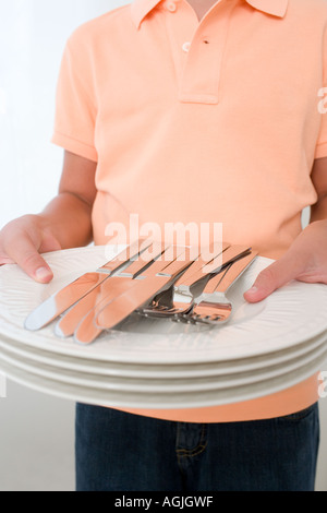 Boy holding assiettes et couverts Banque D'Images