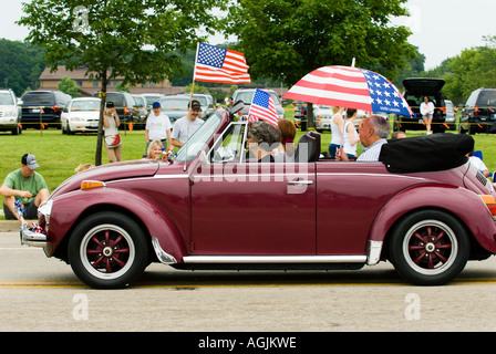 Les cavaliers patriotique dans un bourgogne Volkswagen Beetle convertible participer à un défilé du 4 juillet Banque D'Images