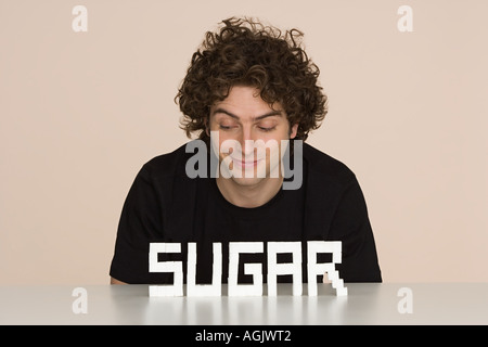 Jeune homme avec du sucre sur une table Banque D'Images