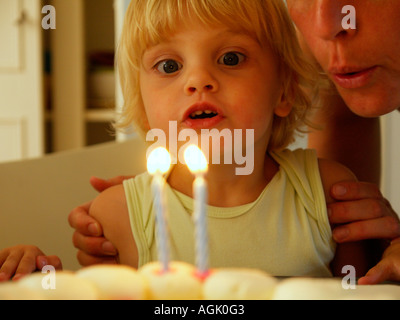 Little girl blowing out deux bougies allumées sur son deuxième anniversaire de son nom est Irene Banque D'Images