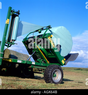 Les balles rondes d'être enveloppée d'un tracteur et l'équipement de l'ensilage dans Carmarthenshire Wales UK Banque D'Images