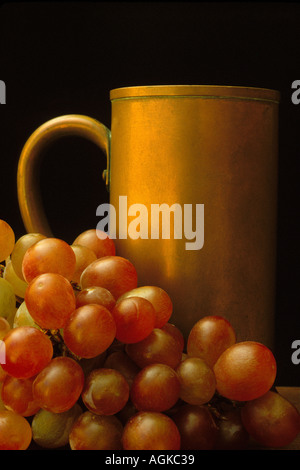 La vie encore chaud : cuivre tasse et raisins rouges dans la chaude lumière USA Banque D'Images