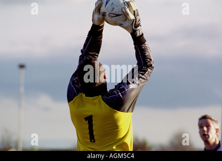 Gardien de but attraper une balle au cours d'un match de football amateur, Suffolk, UK. Banque D'Images