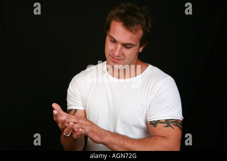 Fit young handsome attrayants les tondeuses 20s'appliquer l'hydratant de la peau Produits de la peau pour hommes en préparation pour une nuit Banque D'Images