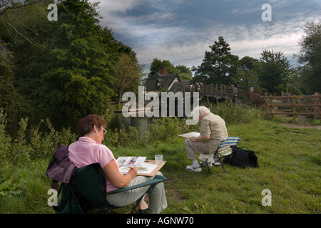 Deux femmes artistes peinture le pont à leur chalet dans le Suffolk, Angleterre Flatford Historique Banque D'Images