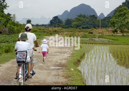 Chine Guangxi Yangshuo Young Chinese Man Riding un tandem avec un garçon européen le long des rizières Banque D'Images