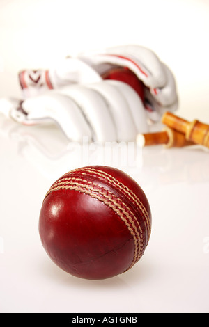 Une balle de Cricket marron rouge rond avec deux une paire de gants et deux boites woodden en arrière-plan sur le couvercle blanc Inde verticale Banque D'Images