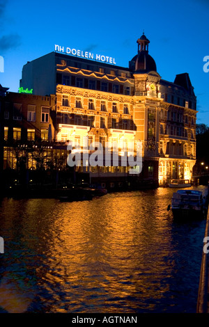 Le NH Doelen Hotel avec des lumières sur la nuit le long de la rivière Amstel à Amsterdam Pays-Bas Banque D'Images