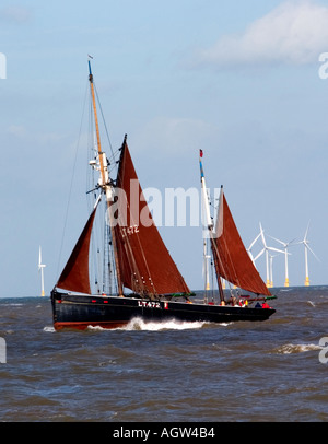 Vieux bateau de pêche voiles passé gt yarmouth wind farm Banque D'Images