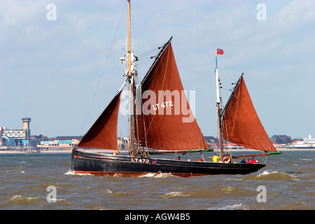 Vieux bateau de pêche voiles passé gt yarmouth wind farm Banque D'Images