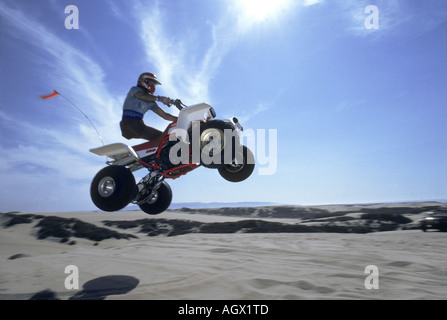 Un véhicule tout terrain est à l'air et vole sur des dunes de sable à un California beach Banque D'Images