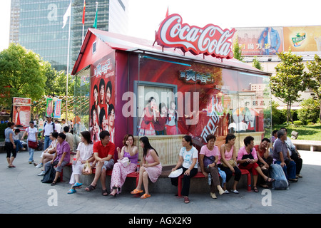 Les travailleurs s'asseoir à l'ombre à l'heure du déjeuner en face de la publicité de Coca Cola à Shanghai's popular Xiang Yang Market Fashion Banque D'Images