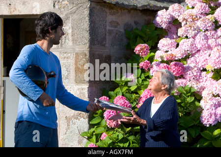 Transporteur lettre française la distribution du courrier à une femme edlerly dans le village de Barfleur dans la région de Basse Normandie France Banque D'Images