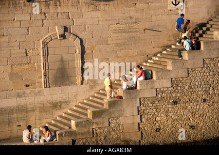 Les gens s'assoient sur les marches de pierre le long de la Seine à Paris France Banque D'Images
