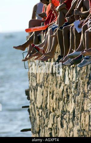 Les jambes et les pieds des spectateurs regardant régate régates assis sur sea wall Puerto Viejo de Algorta Pays Basque Espagne Banque D'Images